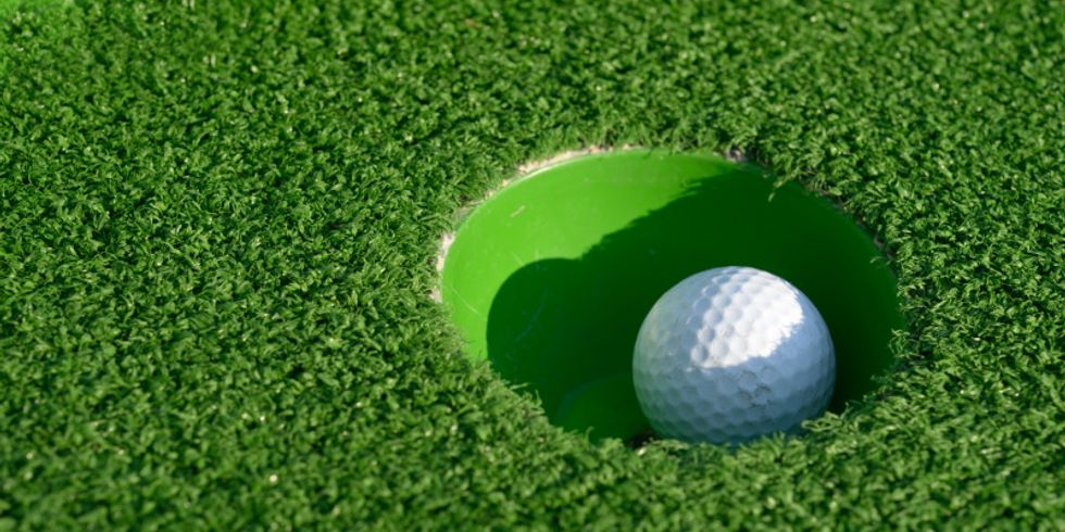 Minigolfball ist auf einer grünen Bahn eingelocht