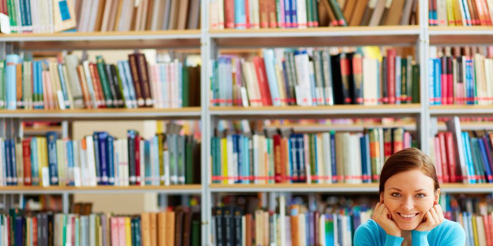 Junge Frau mit vielen Büchern im Hintergrund