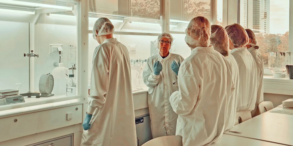 Menschen in Kitteln stehen in einem Labor zusammen