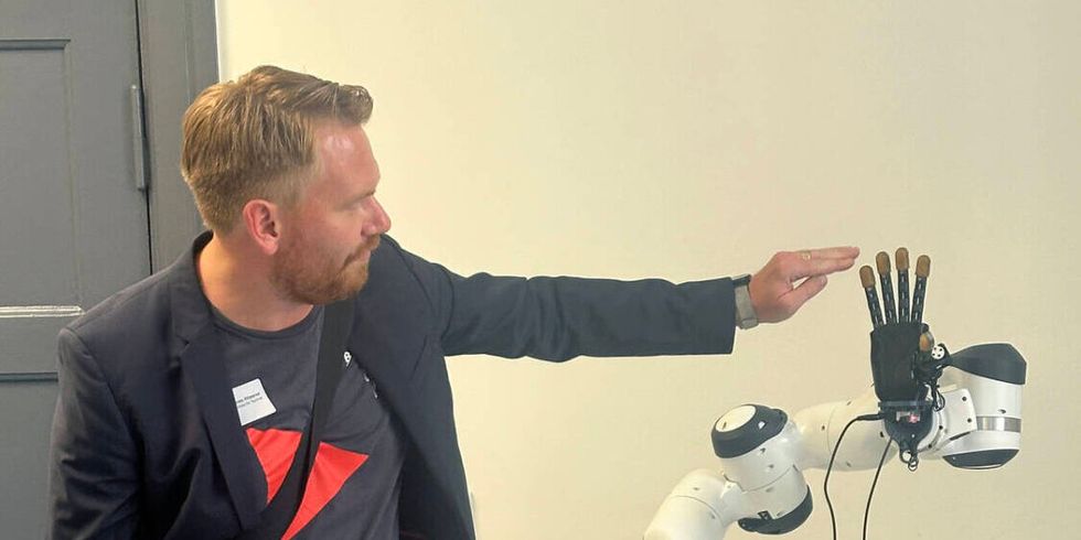Ein junger Mann berührt während einer Präsentation eine Hand eines Roboters