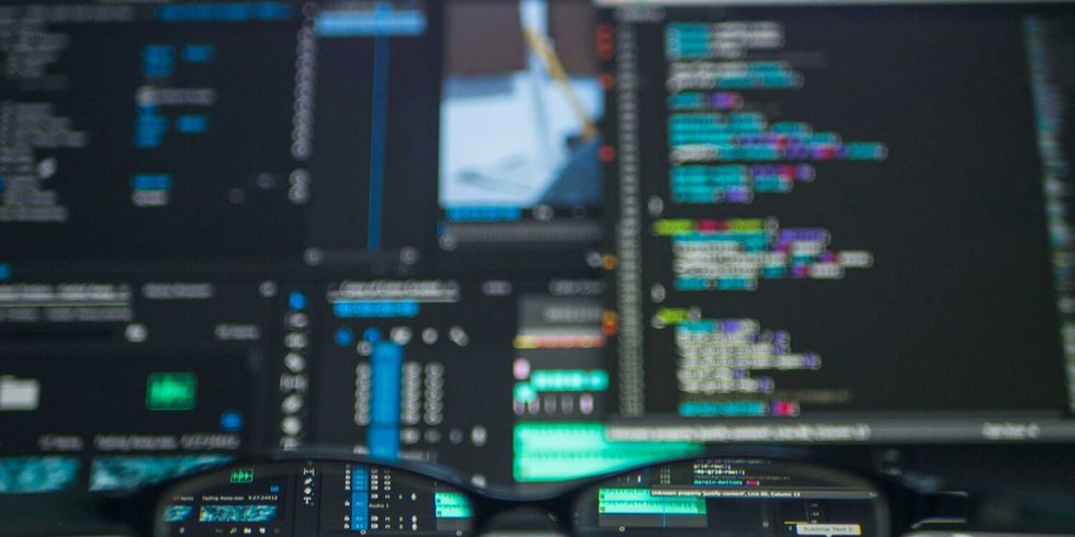 Eine Brille liegt vor einem Monitor mit Computercode