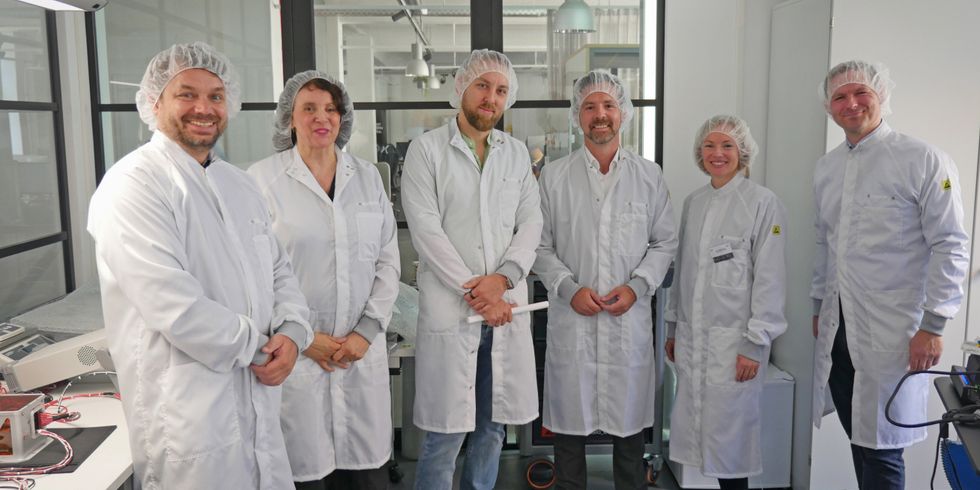 Eine Gruppe von Wissenschaftlern in weißen Kitteln und Haarhauben