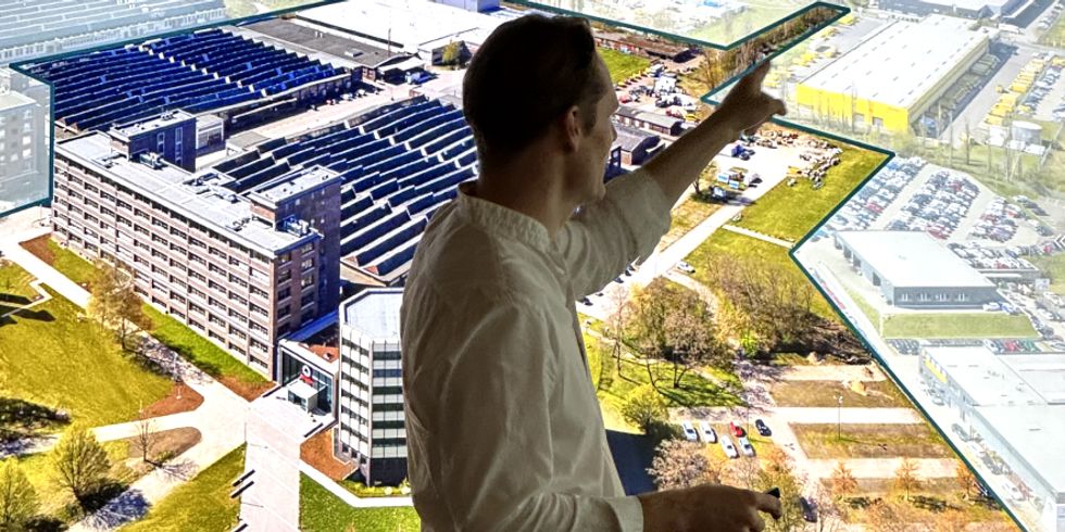 Mann zeigt auf großen Bildschrim mit Satellitenbildern von Häusern