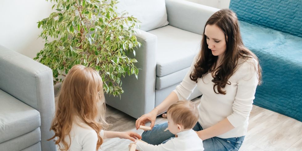 Mama mit zwei Kindern beim Spielen auf dem Fußboden