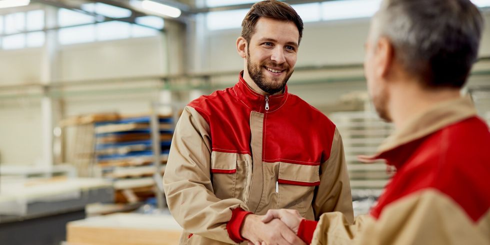 2 arbeitende Personen geben sich freundlich die Hand in einem Werk.