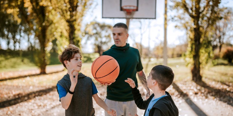 Drei Menschen, zwei davon Kinder, die Basketball spielen