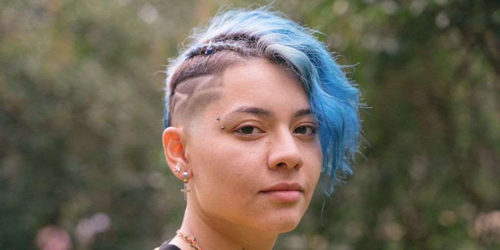 Junge Frau mit Undercut und blauen Haaren und Regenbogenhemd