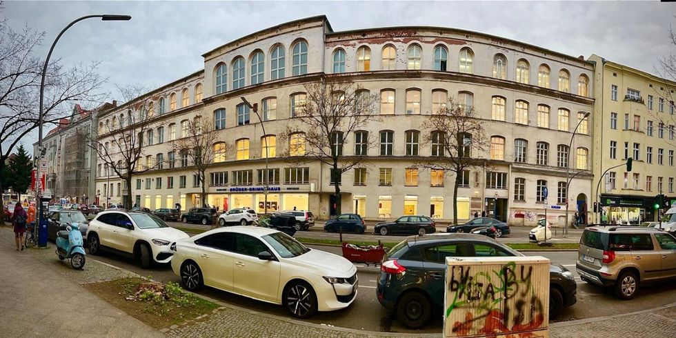 Großes, fünfstöckiges Gebäude an einer mehrspurigen Straße in der Dämmerung.