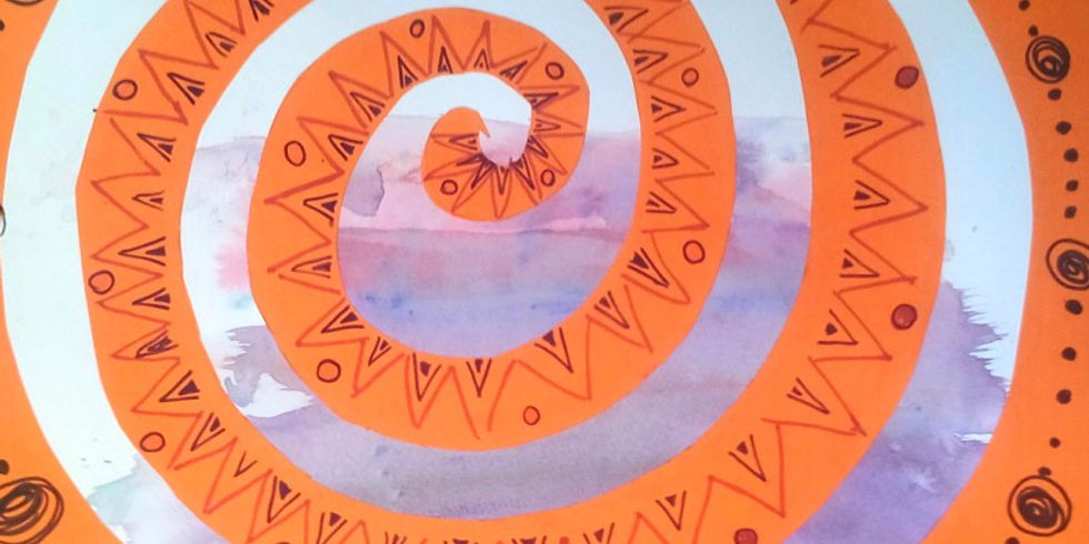 Eine aus Karton ausgeschnittene, orangefarbene Spirale auf bemaltem Papier