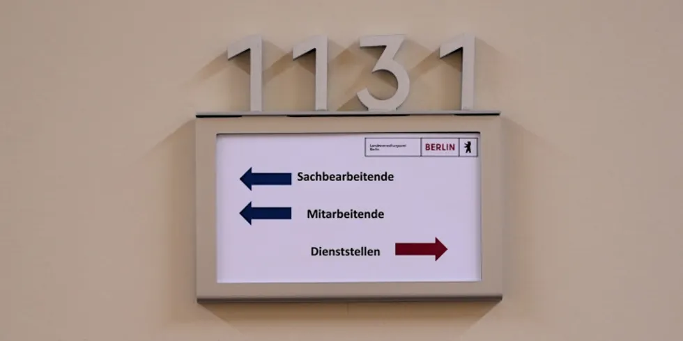 Ein Schild mit abgehenden Pfeilen von Sachbearbeitende, Mitarbeitende und Dienststellen an einer Tür