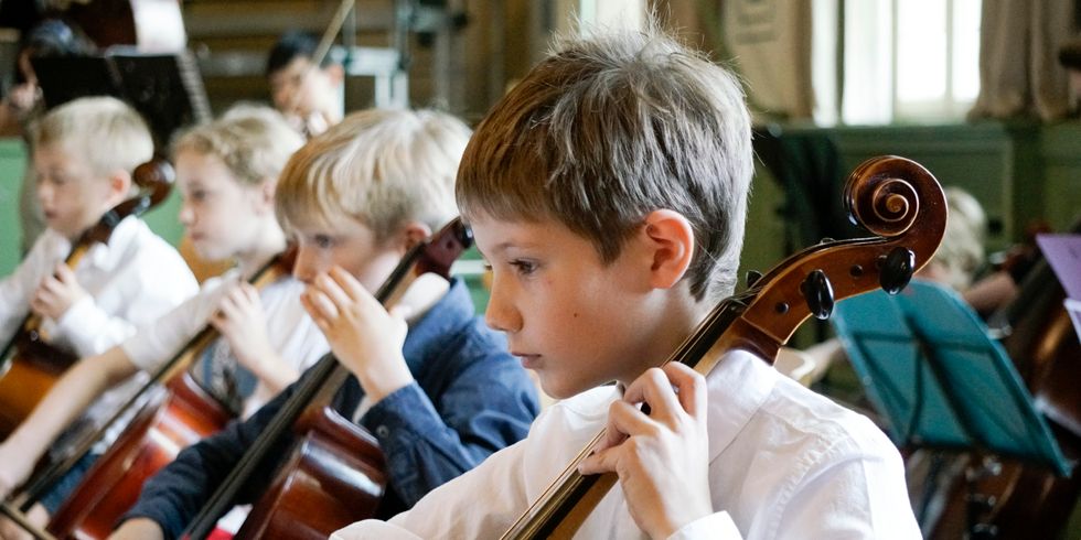 Jungs spielen konzentriert Cello.
