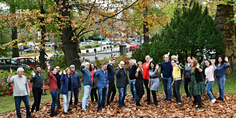 Viele Menschen vor Herbstbäumen winken