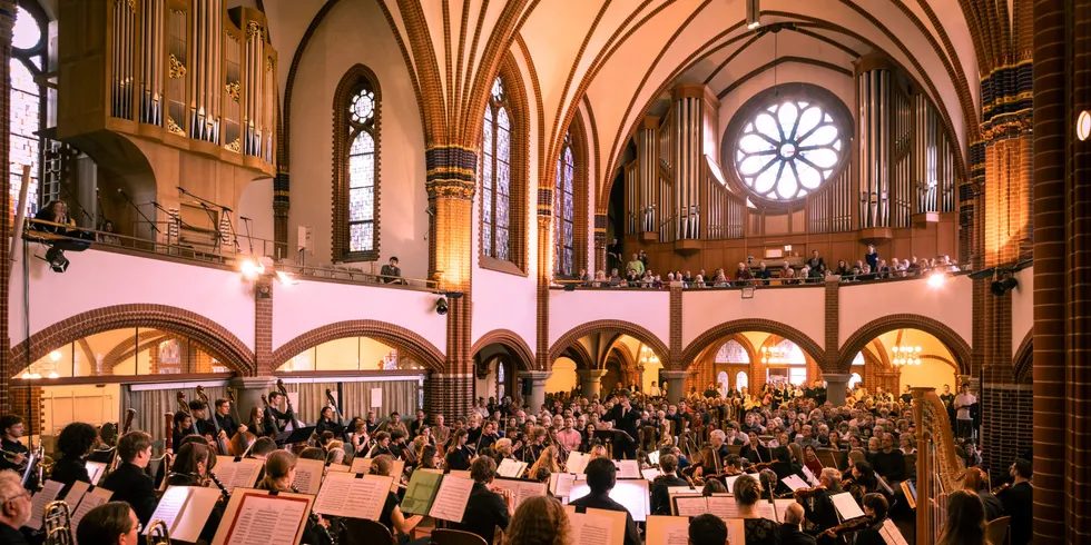 Ein Orchester vor einem großen Publikum in der Pauluskirche Zehlendorf.