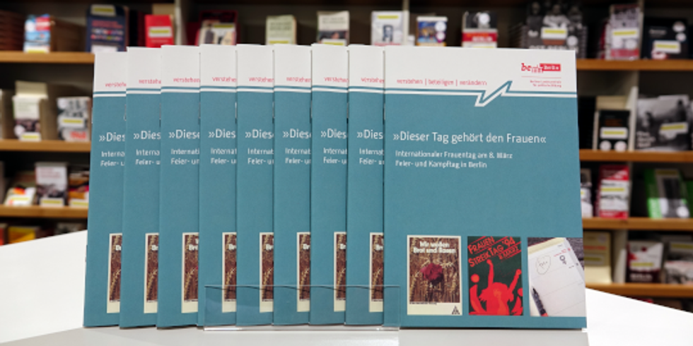 Broschüren zum Internationalen Frauentag am 8. März mit einem Buchregal im Hintergrund
