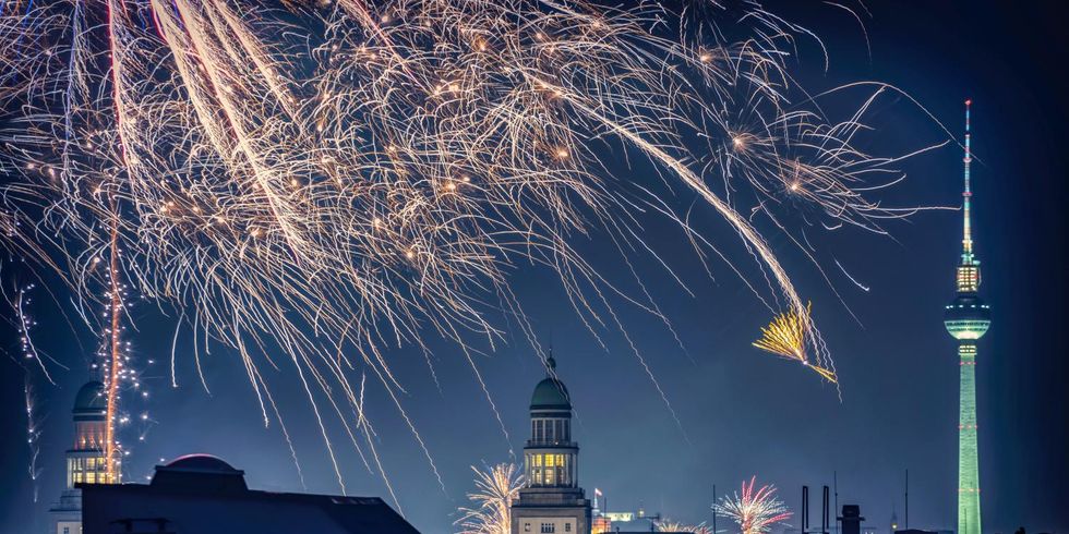 Abendliches Silvester-Feuerwerk mit Silhouette der Stadt Berlin.