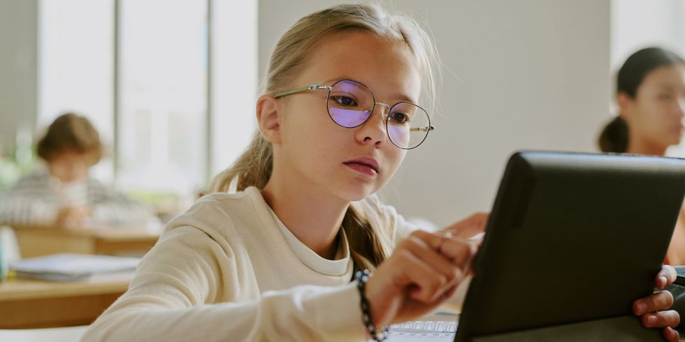 Schülerin sitzt im Klassenraum und arbeitet an einem Tablet