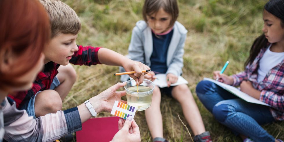 Gruppe von Schülern experimentiert im Freien mit Flüssigkeiten