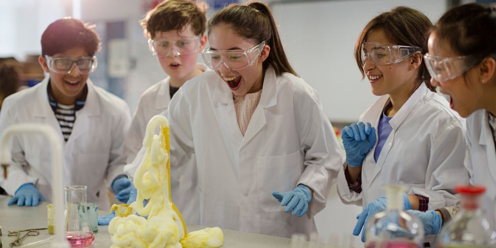 Gruppe von Schülern expertimentiert im Chemieunterricht und freut sich über eine chemische Reaktion
