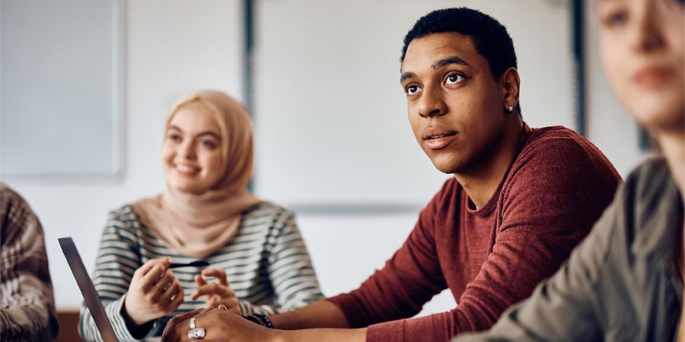 Multiethnische Gruppe Studenten sitzt zuhörend an einem Arbeitstisch