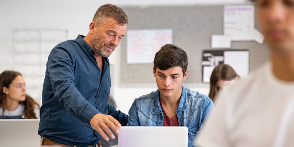 Lehrer unterstützt Schüler am Computer