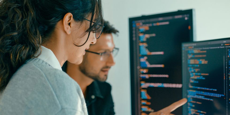 Zwei Menschen sitzen vor einem Computer und codieren