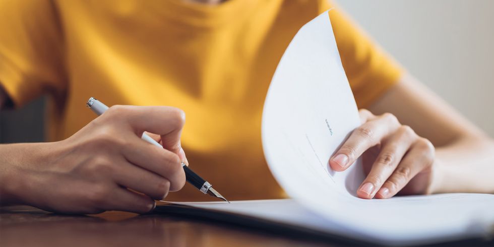 Eine Frau unterzeichnet ein Dokument und hält dabei den Stift in der Hand