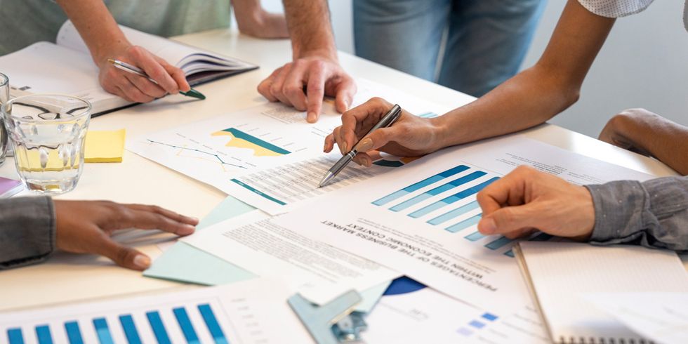 Gruppe von Mitarbeitern arbeitet an einem Finanzplan, Bildausschnit nur auf den Tisch und die Hände