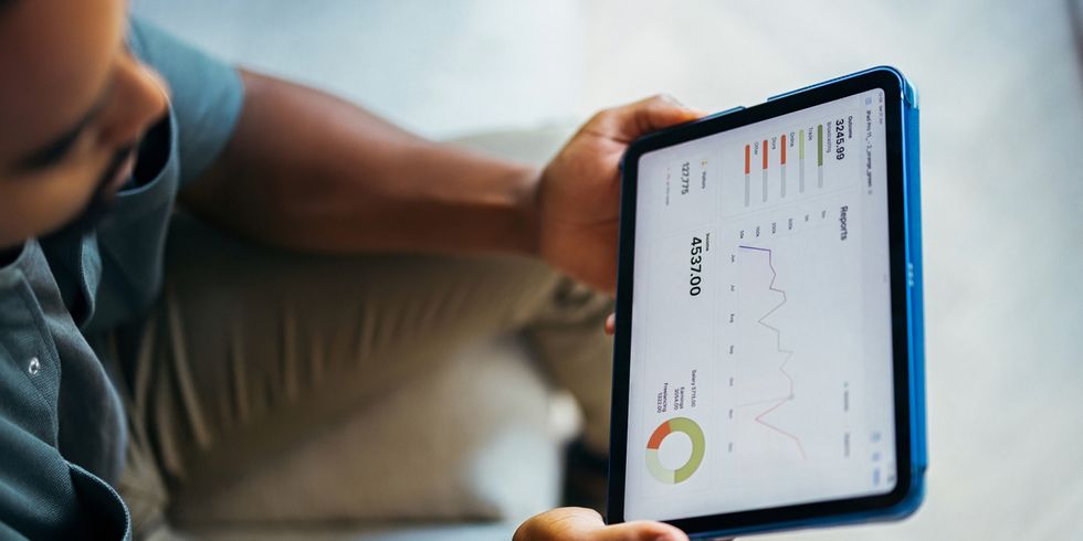 Person hält Tablet mit abgebildeten Statistiken in der Hand