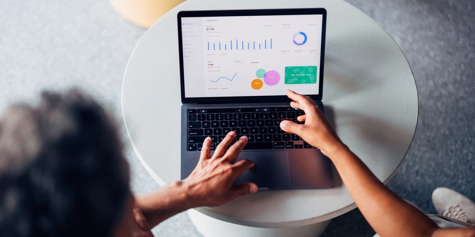 Mann arbeitet an Laptop, auf welchem Statistiken abgebildet sind - Vogelperspektive