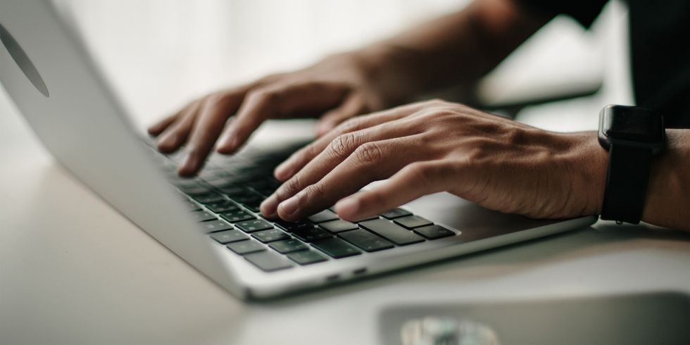 Mann tippt auf Tastatur von Laptop