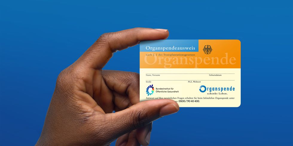 Ein Organspendeausweis wird von einer Hand hoch und frontal in die Kamera gehalten. Der Hintergrund ist blau.