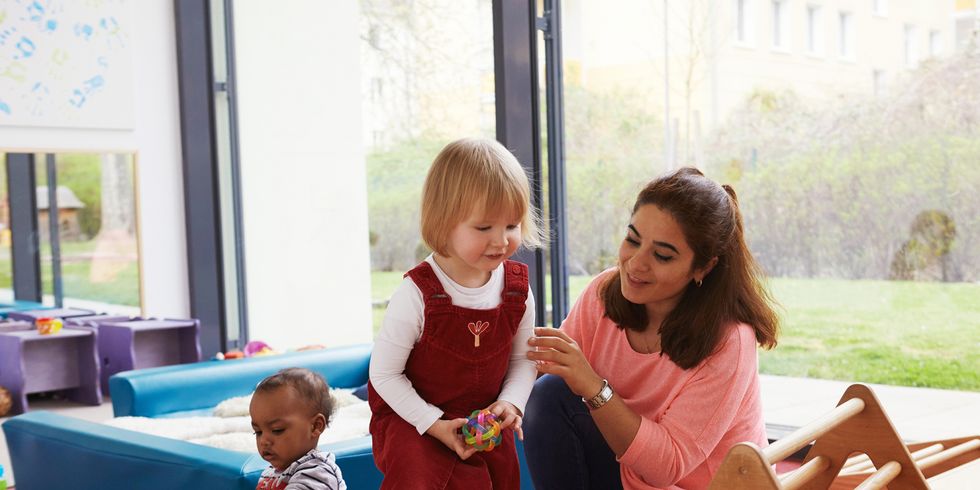 Kinder spielen mit Erzieherin in Kita