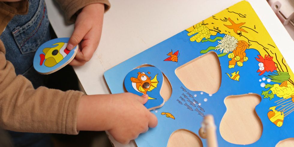 Kind setzt ein Teil in ein Holzpuzzle ein