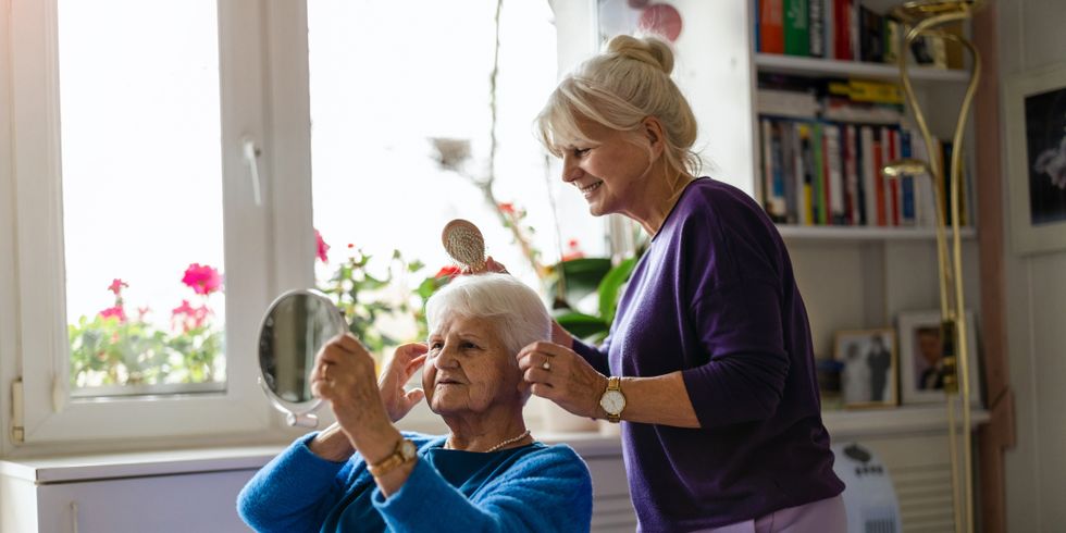 Woman combing hair of elderly mother