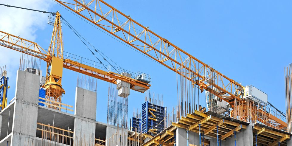 Betonwände eines Neubaus werden mit Hilfe von Kränen hochgezogen