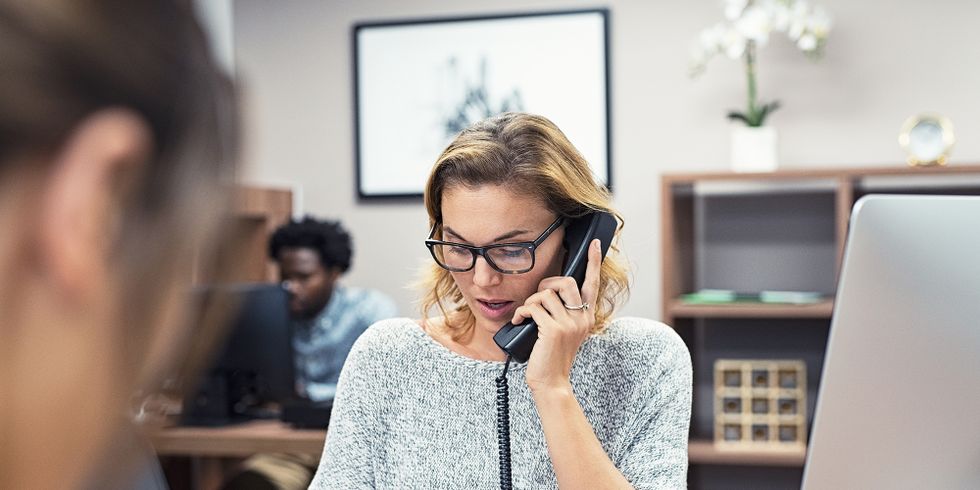 Frau sitzt am Tisch und telefoniert