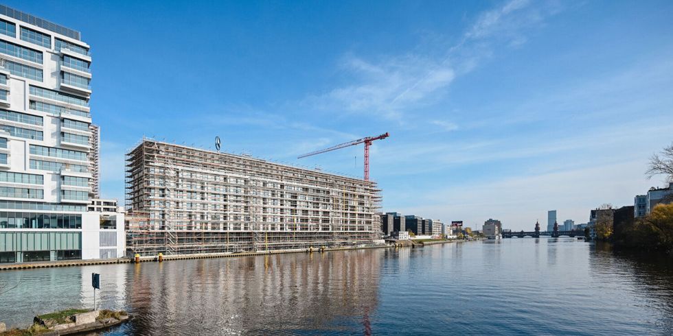 Neubaugebäude am Fluss von Baugerüst umgeben