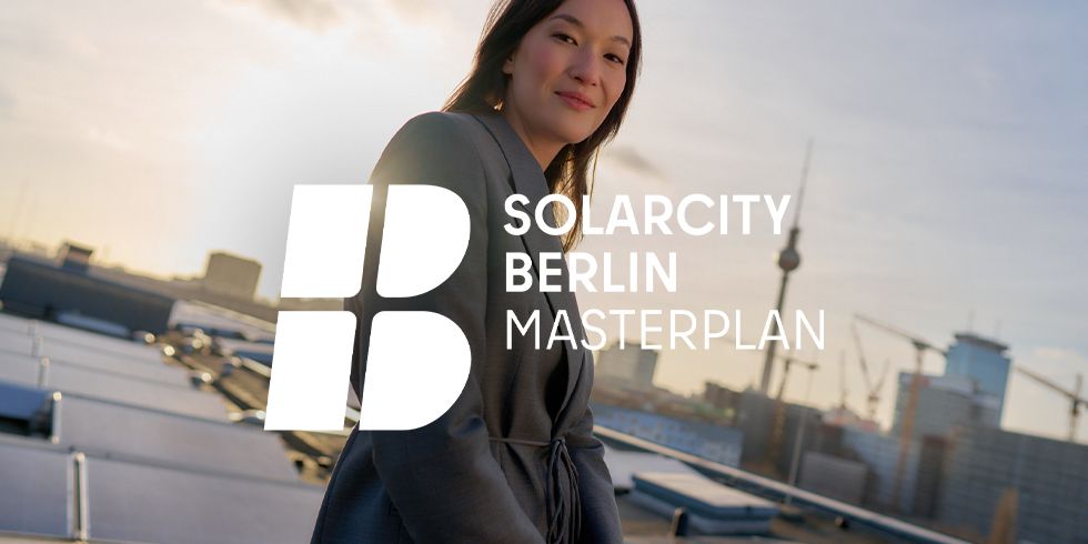 Frau auf Dach, lächelt in Kamera. Hinter ihr eine Photovoltaianlage und ein Ausblick über Berlin.