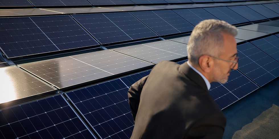 Solarpanel auf einem Dach. Im Vordergrund eine Person die zur Seite aus dem Bild läuft.
