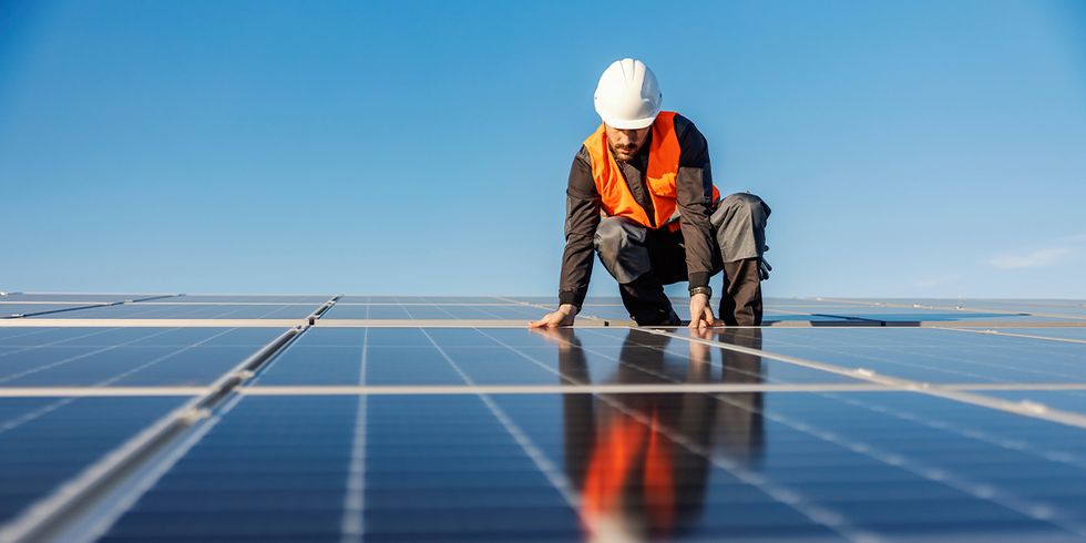 Handwerker auf Dach zwischen Solarpanels