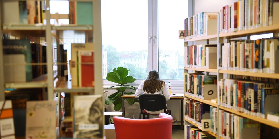 Bettina-von-Arnim-Bibliothek: Frau sitzt am Fenster Blick über die Dächer.