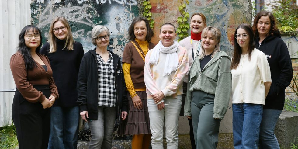 Neun Bibliotheksmitarbeitende stehen im Hof der Bibliothek und lächeln freundlich.