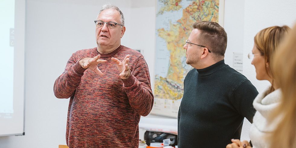 Teilnehmende diskutieren und gestikulieren stehend im Raum