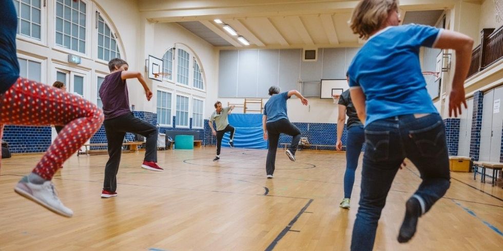 Szene in einer Turnhalle: Mehrere Teilnehmende sind in dynamischer Bewegung
