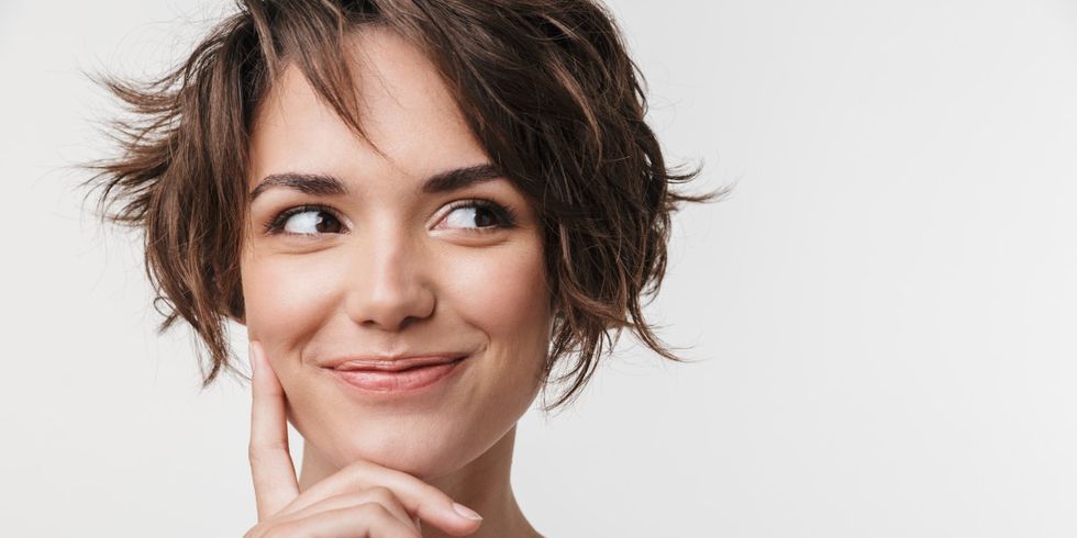Junge Frau schaut ver&shy;schmitzt ins Bild
