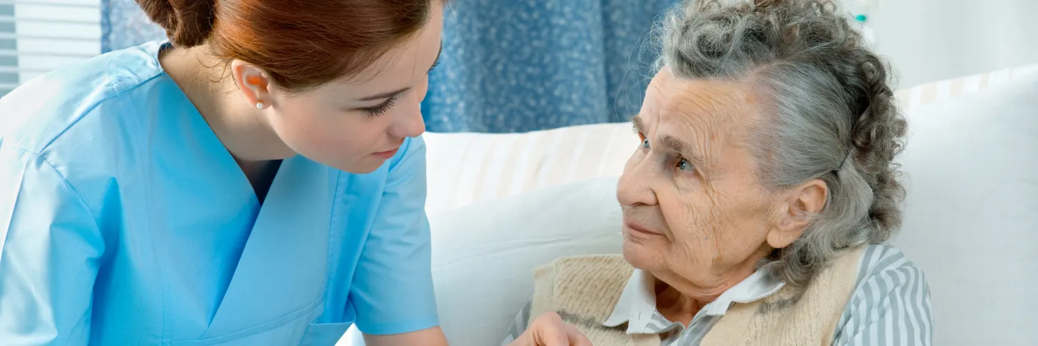 Krankenschwester kümmert sich um eine ältere Frau im Bett liegend