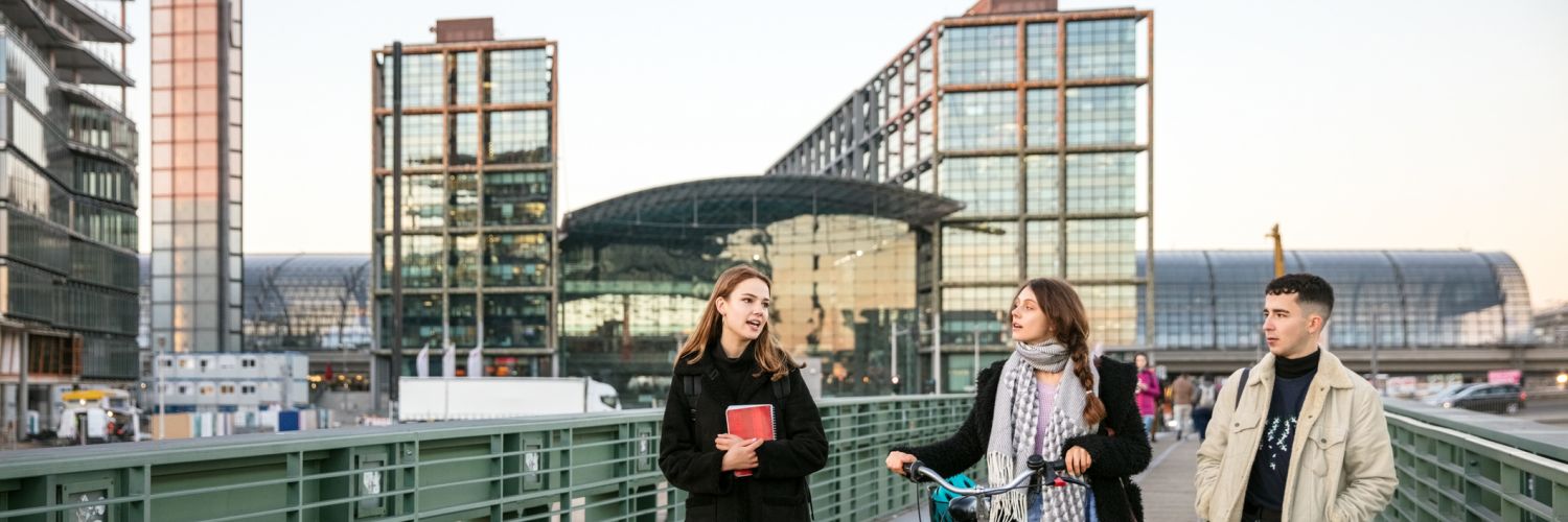 Students together over a pedestrian bridge with bicycle in Berlin, Germany