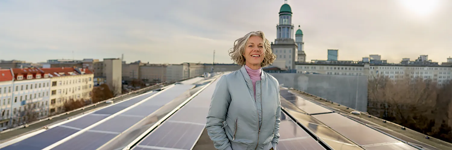 Frau auf Dach in der Petersburger Strasse. Im Hintergrund Solarpanel und die Skyline von Berlin.