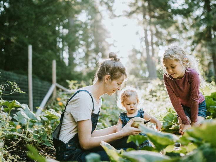 Eine Mutter mit zwei Kindern im Garten