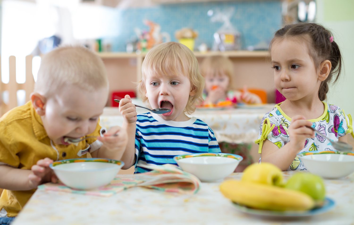 Gruppe von Kindern isst im Kindergarten von Tellern